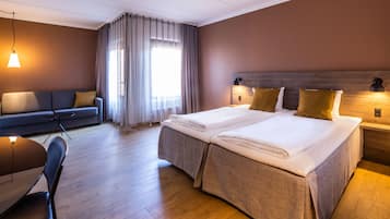 Quarto de hotel com uma cama de casal, um sofá, uma mesa de jantar e um candelabro.