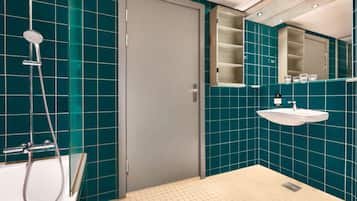 Un baño moderno con azulejos verde mar, un lavamanos blanco y una ducha.
