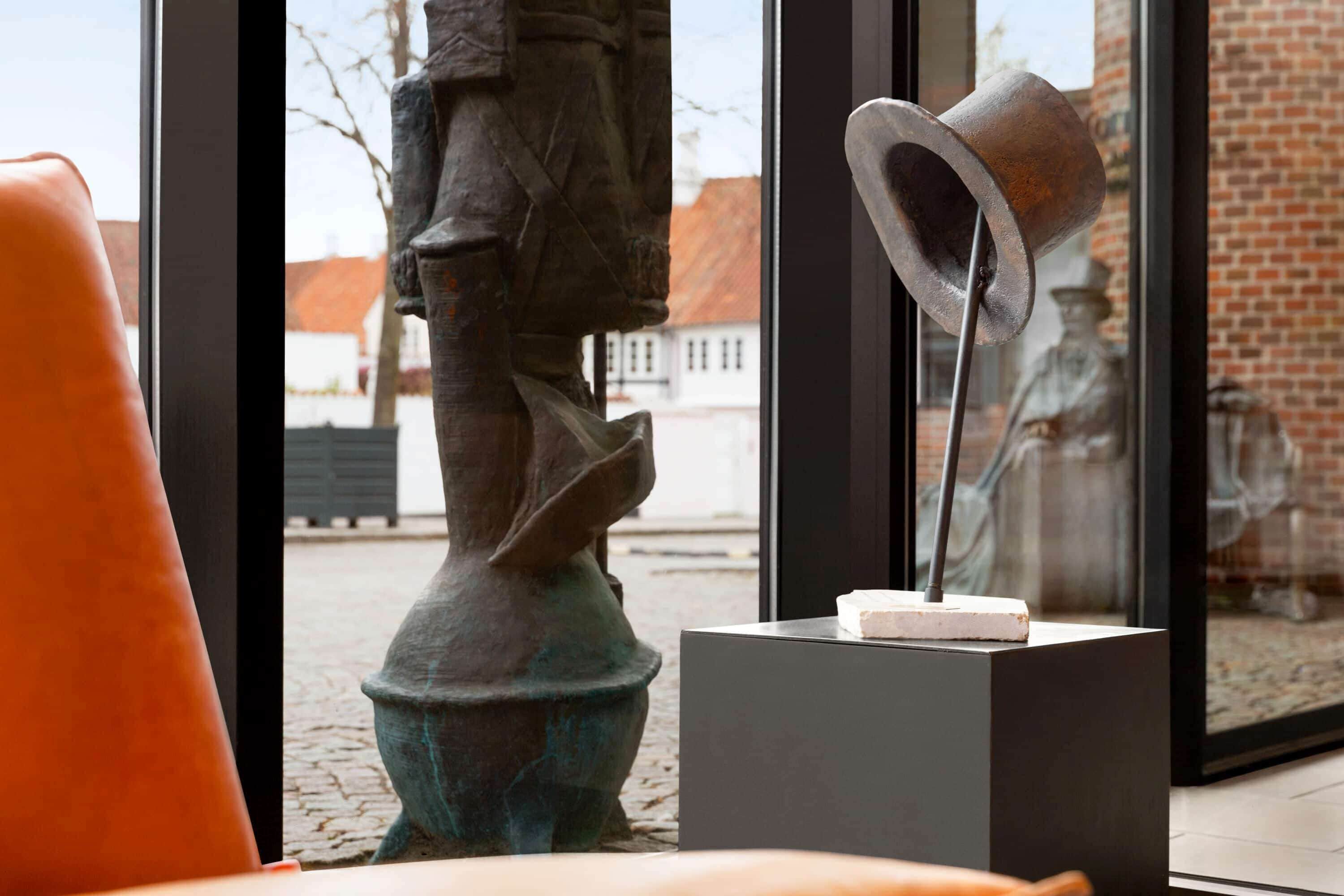 Un interior moderno con una estatua, una escultura de metal y vistas de un edificio de ladrillo.