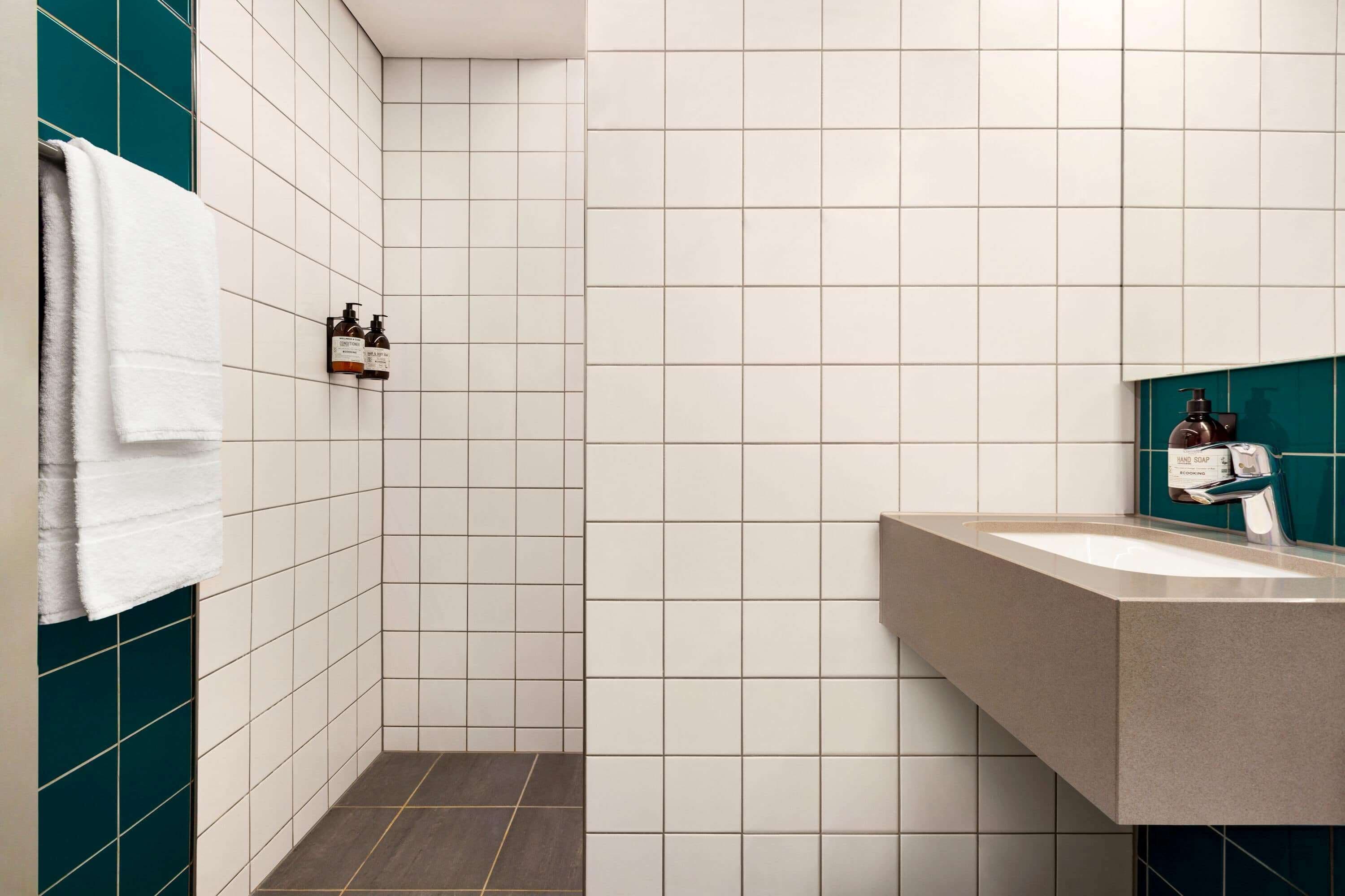 A modern bathroom with white tiles, a sink, and a towel rack.