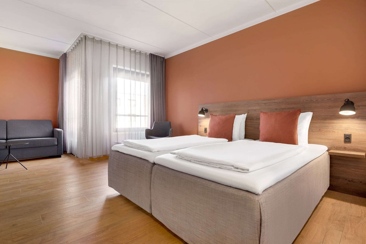 A hotel room with a large bed, a sofa, and a desk.
