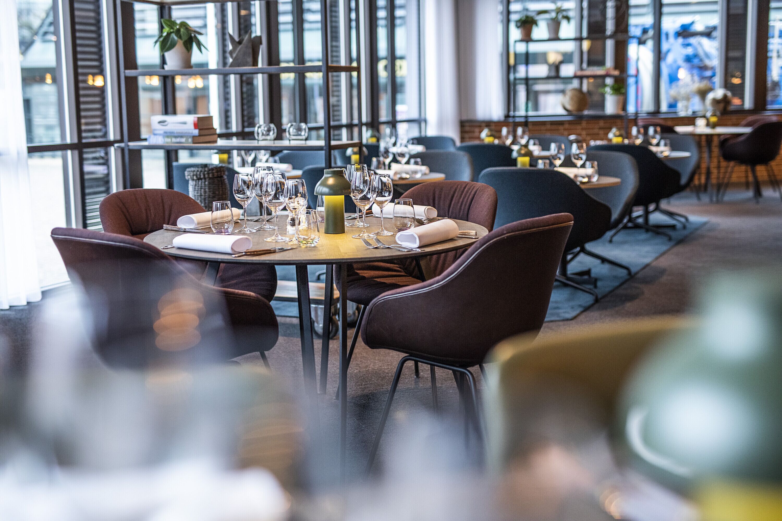 A restaurant with tables set for dining, chairs, and wine glasses.