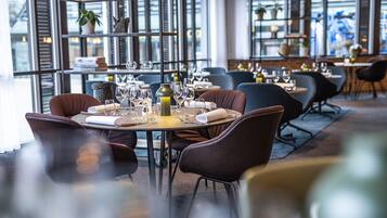 A restaurant with tables set for dining, chairs, and wine glasses.