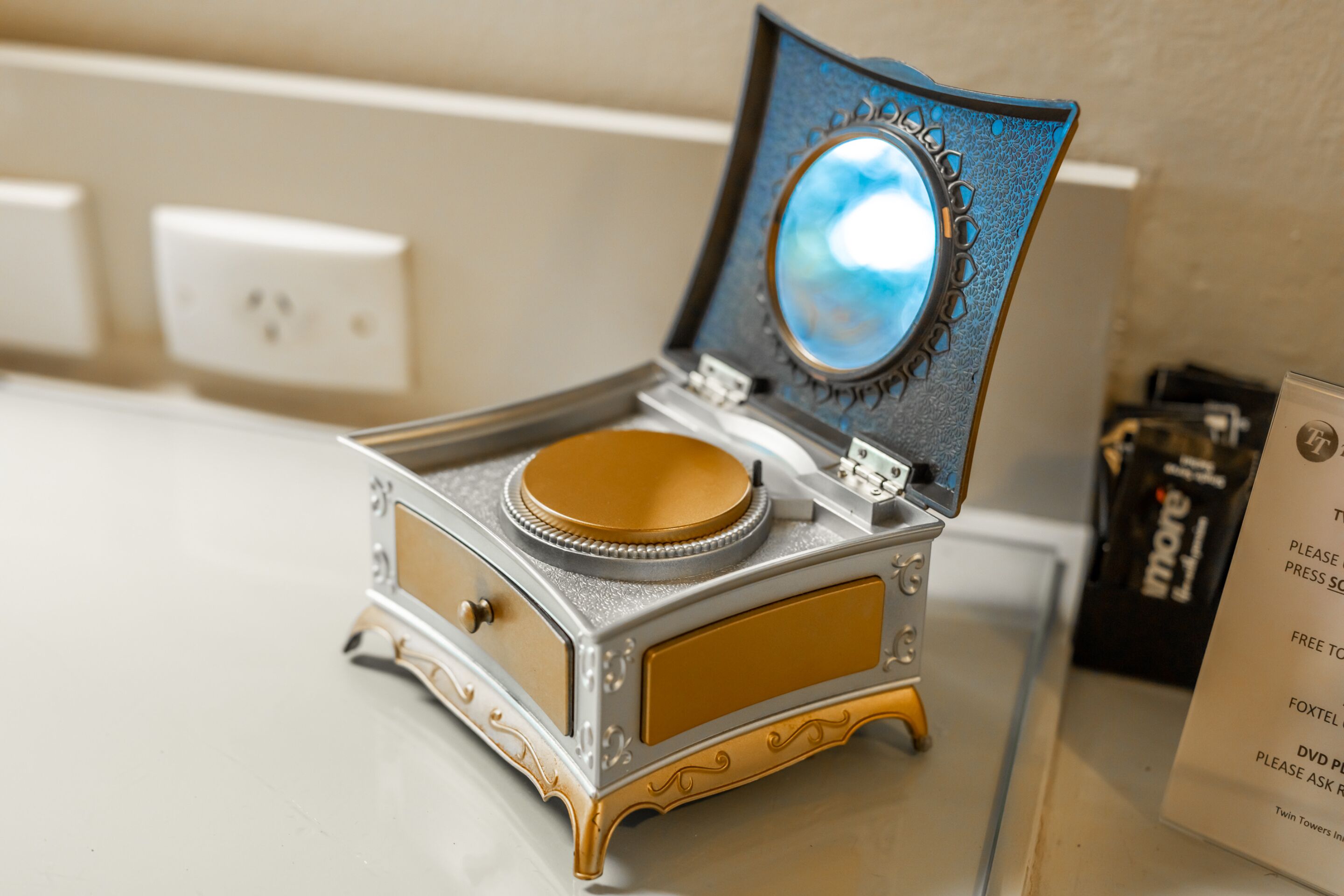 Un gramophone ancien, doté d’une surface réfléchissante et d’un socle décoratif, est posé sur un comptoir.