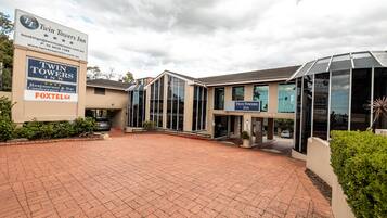The Twin Towers Inn with a paved driveway, large signage, and modern architecture.