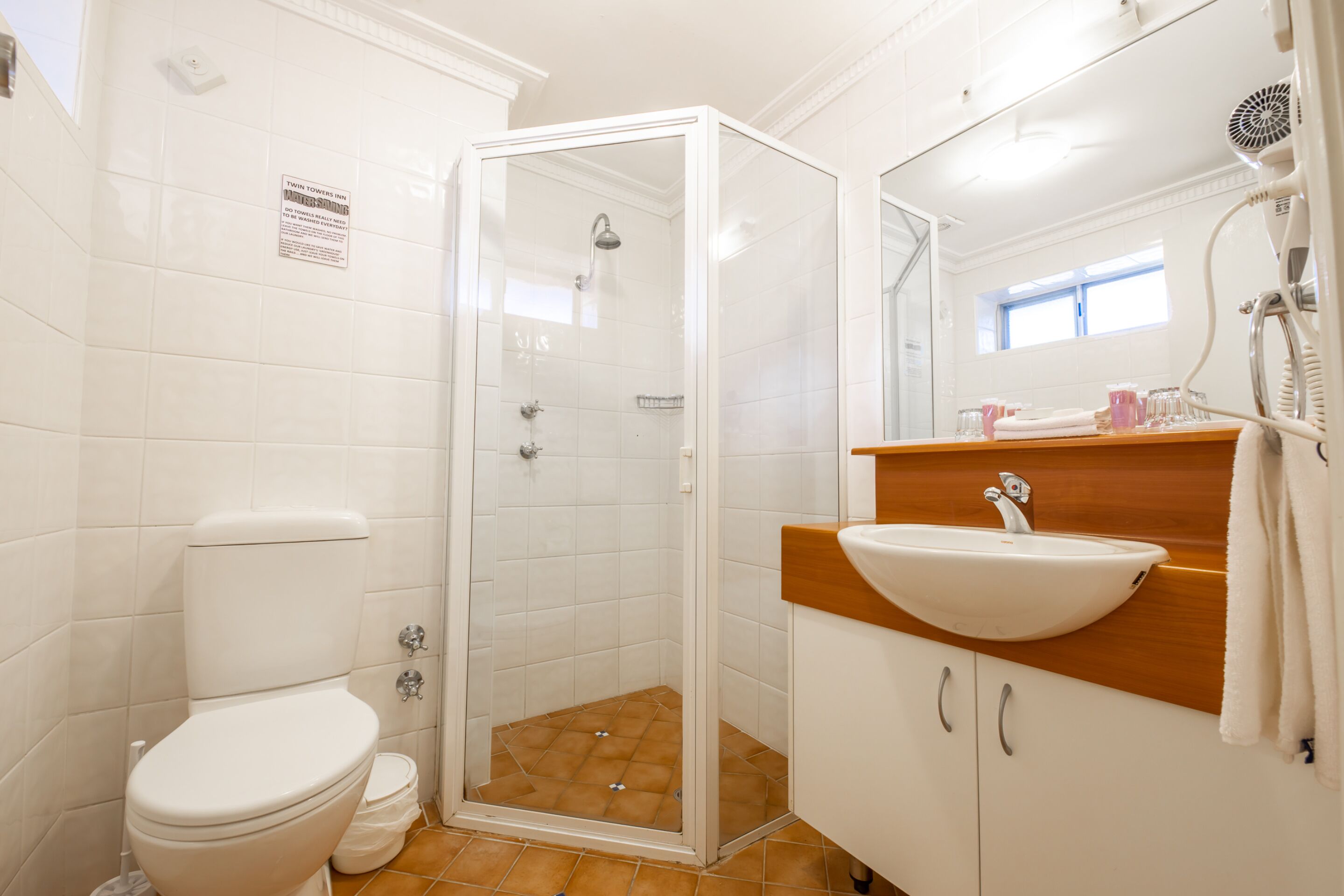 A bathroom with a glass-enclosed shower, a white toilet, and a wooden vanity with a sink.