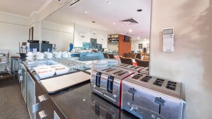 Eine moderne Hotelküche mit Edelstahlgeräten, einem Buffet und einer Sitzgelegenheit im Hintergrund.