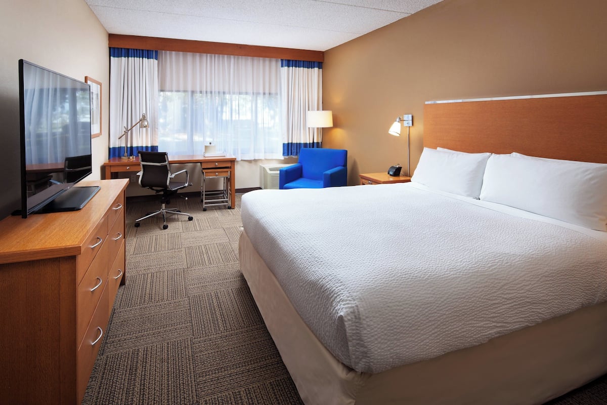 Een hotelkamer met een groot bed, een bureau met een computer, een stoel en een televisie.
