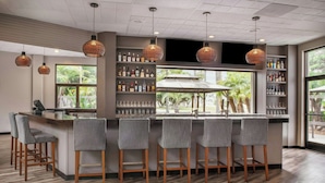 A bar area with a long counter, bar stools, and hanging wicker pendant lights. - Four Points by Sheraton San Diego (San Diego)