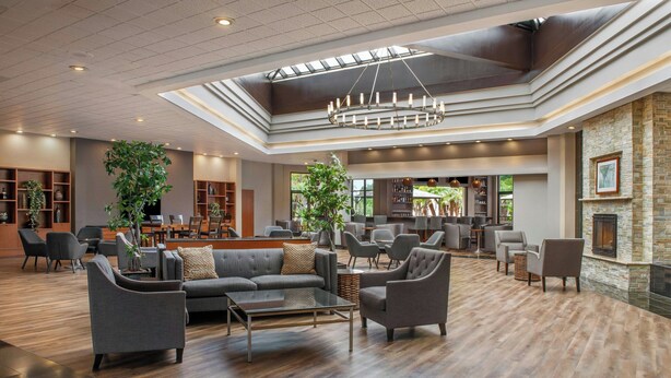 A spacious lobby with a high ceiling, modern furniture, and a fireplace. - Four Points by Sheraton San Diego (San Diego)