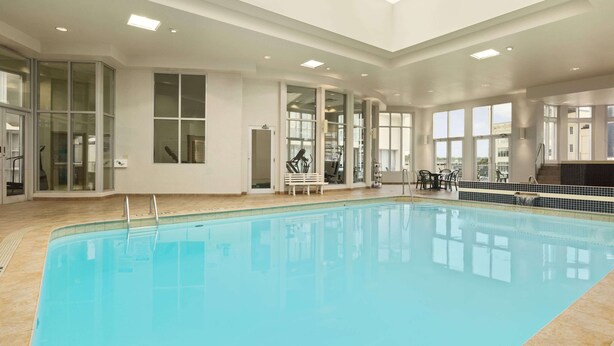 Una piscina interior con paredes de vidrio transparente, suelo de baldosas y tragaluces.