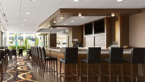 Un vestíbulo de hotel con zona de bar, asientos y vistas al exterior.