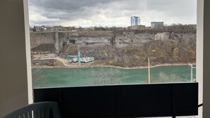 Vista desde una ventana sobre un río, un risco rocoso y edificios a lo lejos.