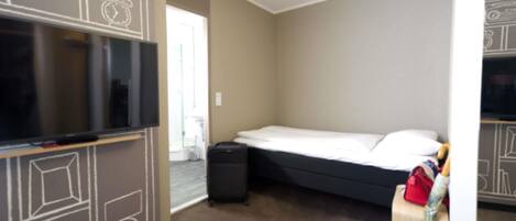 A hotel room with a bed, a television, a suitcase, and a wall with a geometric pattern.