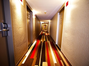 Stylishly designed hallway with patterned carpet and textured walls, offering easy access to guest rooms.