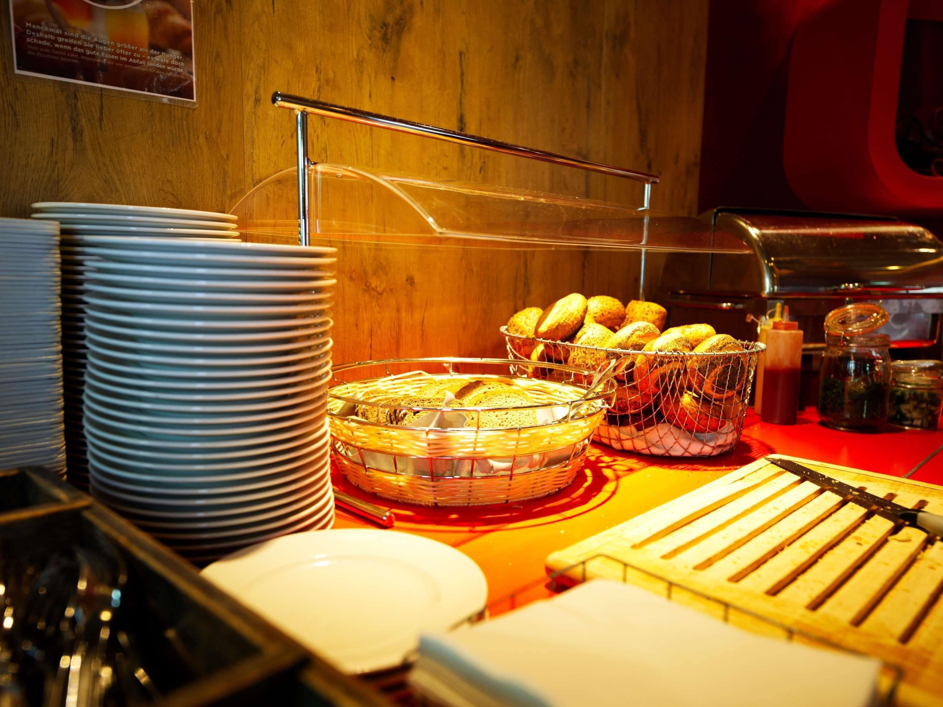 Un buffet avec des assiettes, des paniers de pain, des condiments et une plaque chauffante.