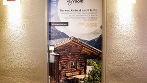Een hotelingang met een poster die een kamer laat zien met uitzicht op een berg, een houten chalet en een bord met het nummer 318.