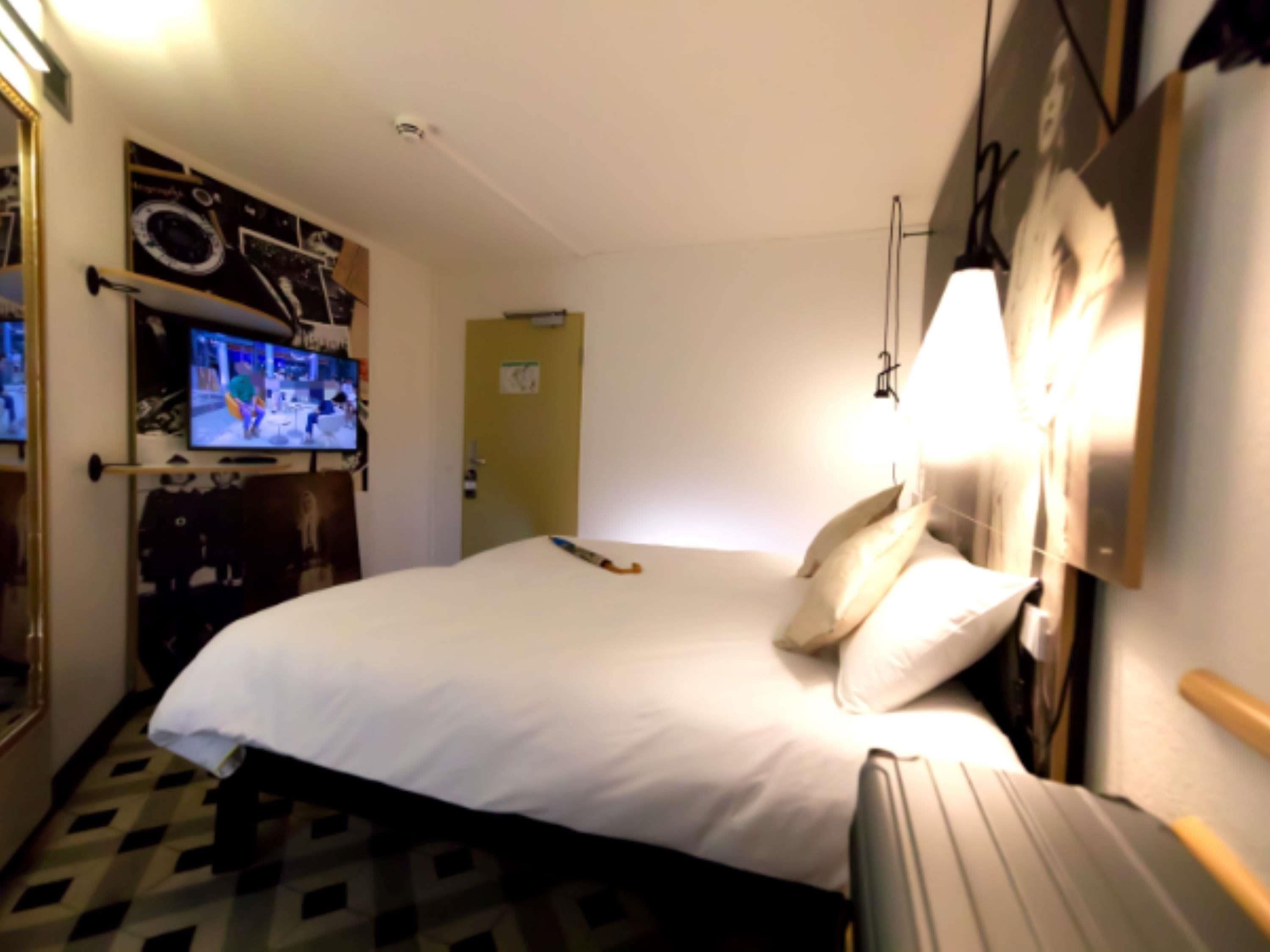 Ein Hotelzimmer mit einem Bett, einem an der Wand befestigten Fernseher und einer Tür.