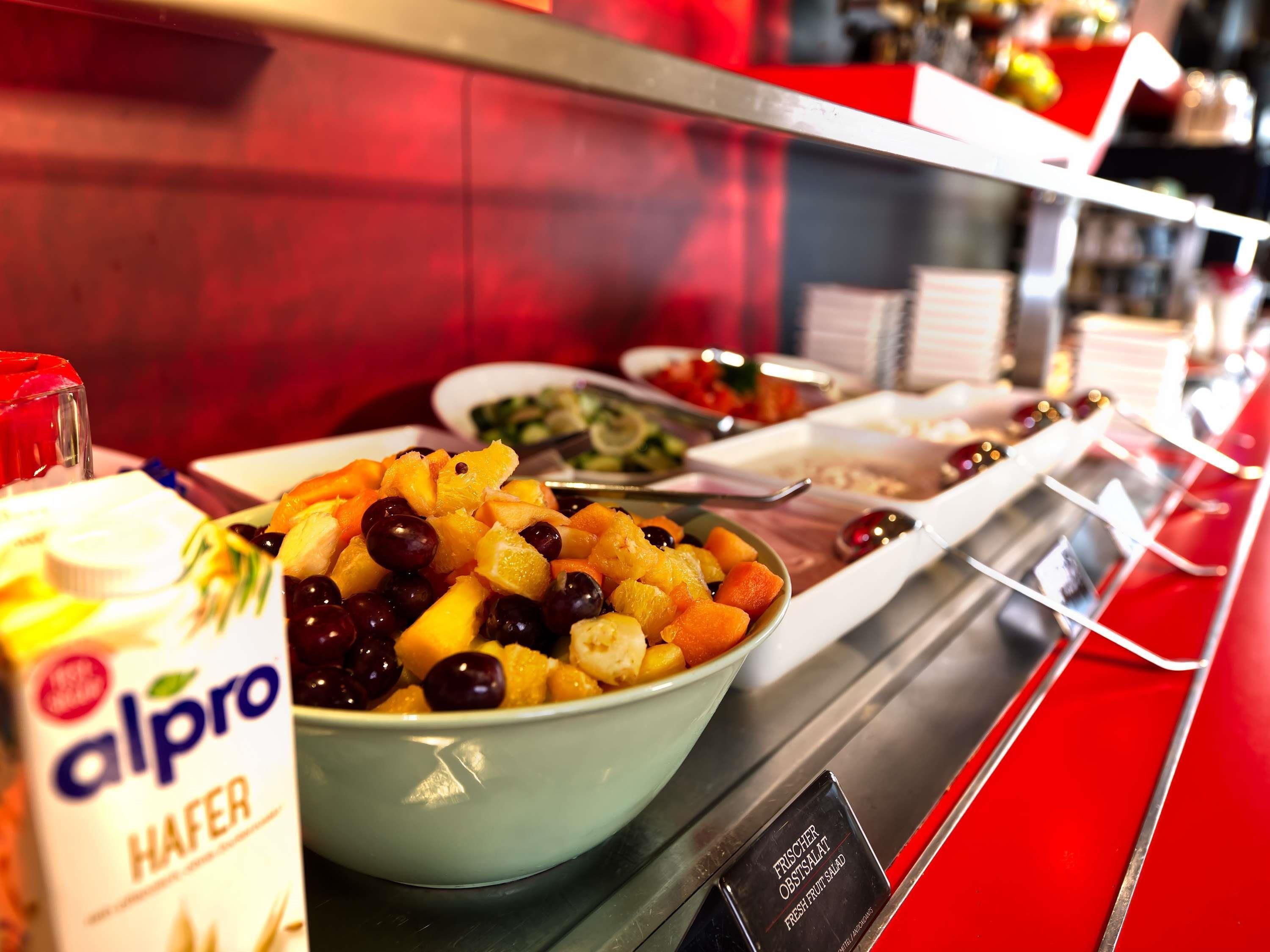 A buffet with a bowl of fruit salad and a container of alpro HAFER.