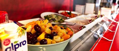 A buffet with a bowl of fruit salad and a container of alpro HAFER.