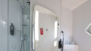 Een moderne badkamer met een douchecabine van glas, een wit wastafelmeubel, een spiegel en een toilet.