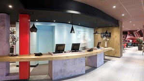 A reception desk with a modern design, featuring a curved counter and a large reception area with a digital screen displaying "RECEPTION" and "ZIMMERWELLE".