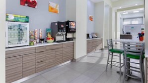 A modern kitchen area with a refrigerator, coffee machines, and a fruit bowl. - Quality Inn University North I-75 (Gainesville)