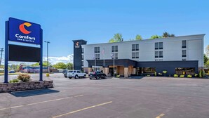 A Comfort Inn & Suites with a modern building, a parking lot, and American flags.