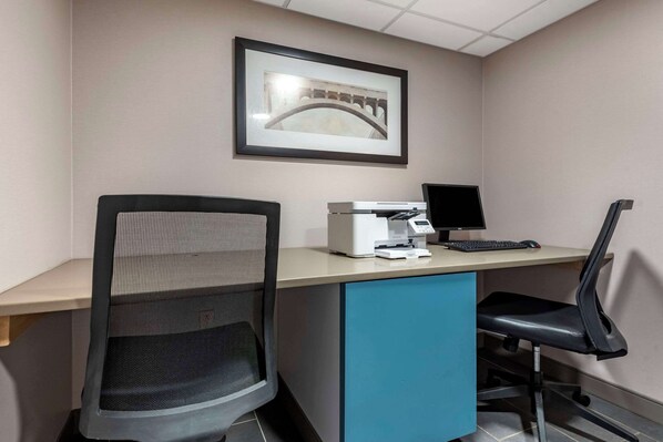 A modern office space with a desk, computer, printer, and two chairs.