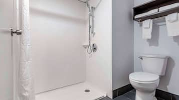 A bathroom with a white shower enclosure, a toilet, and a towel rack.
