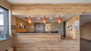 A reception desk with a wooden finish, pendant lighting, framed pictures on the wall, and a window on the left.