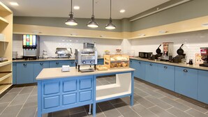 A kitchen area with blue cabinets, a central island, and various appliances like a coffee machine and a waffle maker.