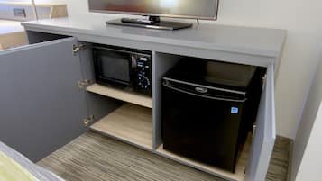 A kitchenette with a microwave, refrigerator, and a flat-screen TV on a countertop.