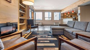 A modern living room with a sectional sofa, a flat-screen TV, and a wooden bookshelf.
