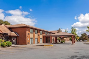 A multi-story hotel with a brick facade, large windows, and a covered parking area.