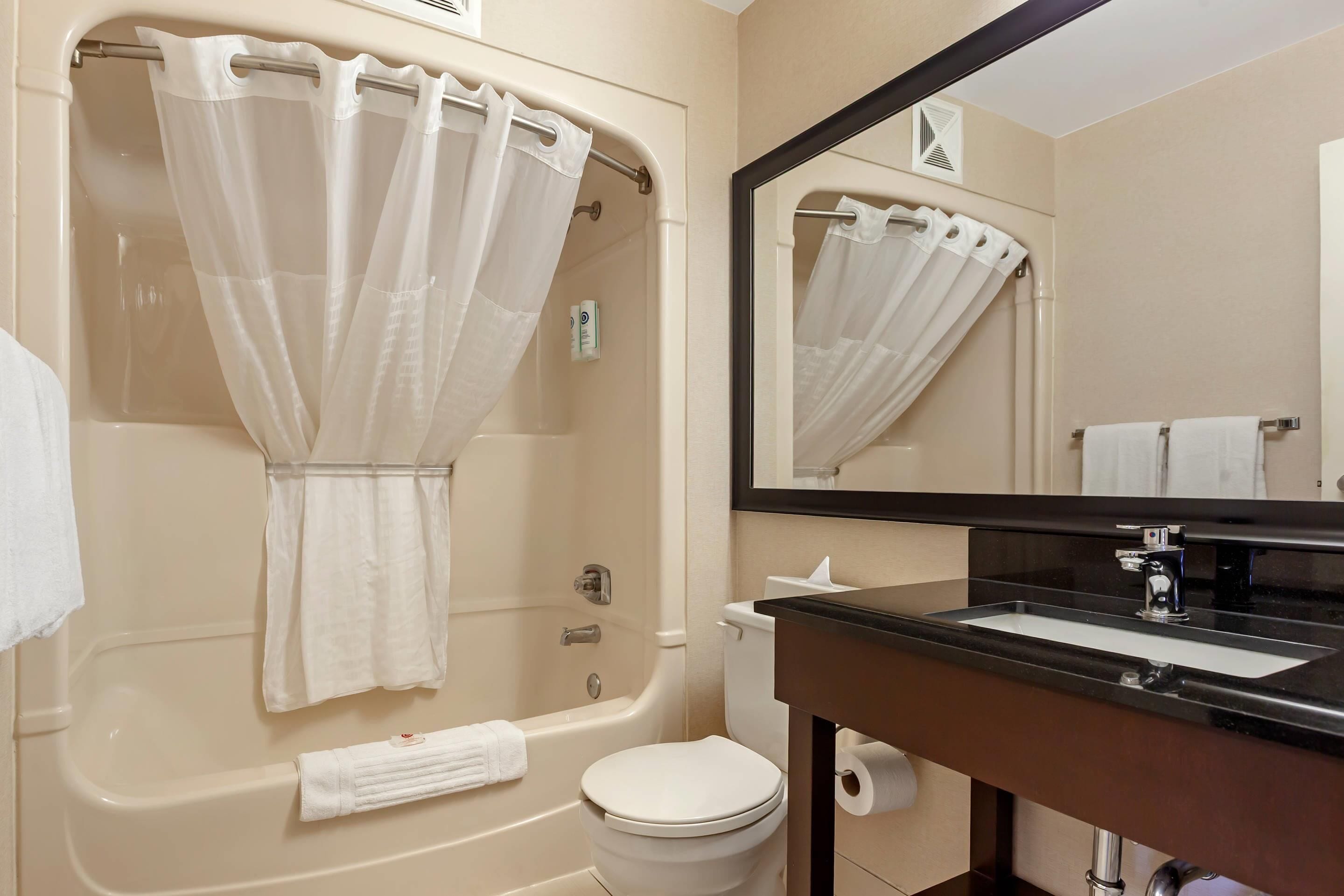 A bathroom with a bathtub, toilet, sink, and a mirror.