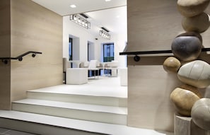 A modern interior with a staircase leading to a seating area with white furniture. - Hyatt Grand Central New York (New York)