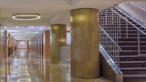 A modern hotel lobby with a long corridor, large cylindrical columns, and a staircase with patterned carpet. - Hyatt Grand Central New York (New York)