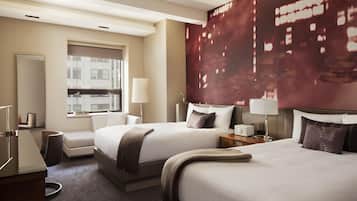 A hotel room with two beds, a desk, a chair, a window, and a large wall mural.
