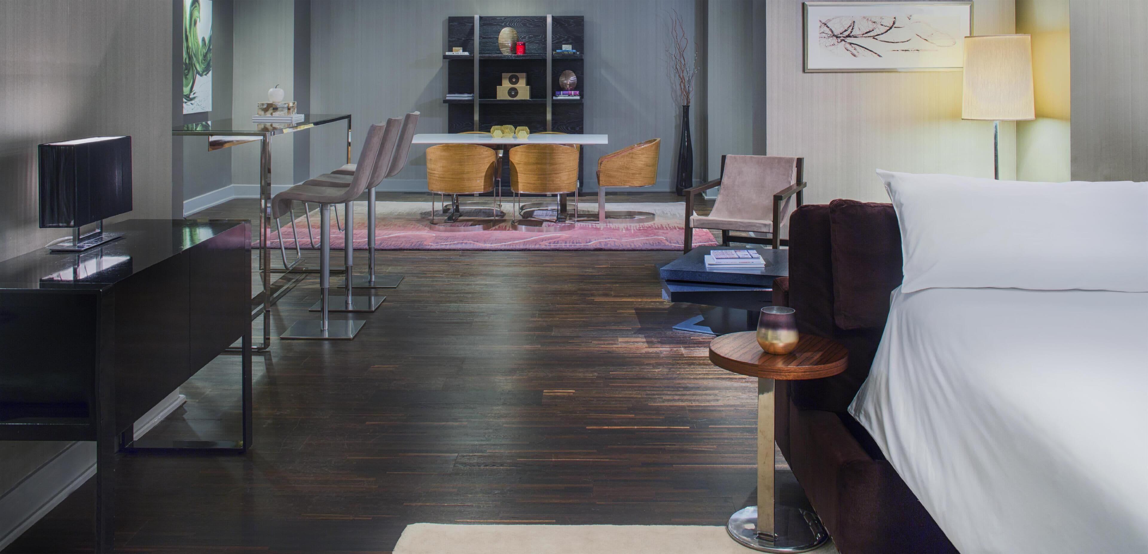 Een hotelkamer met een bed, een bureau, een stoel, een klein tafeltje en een boekenplank.