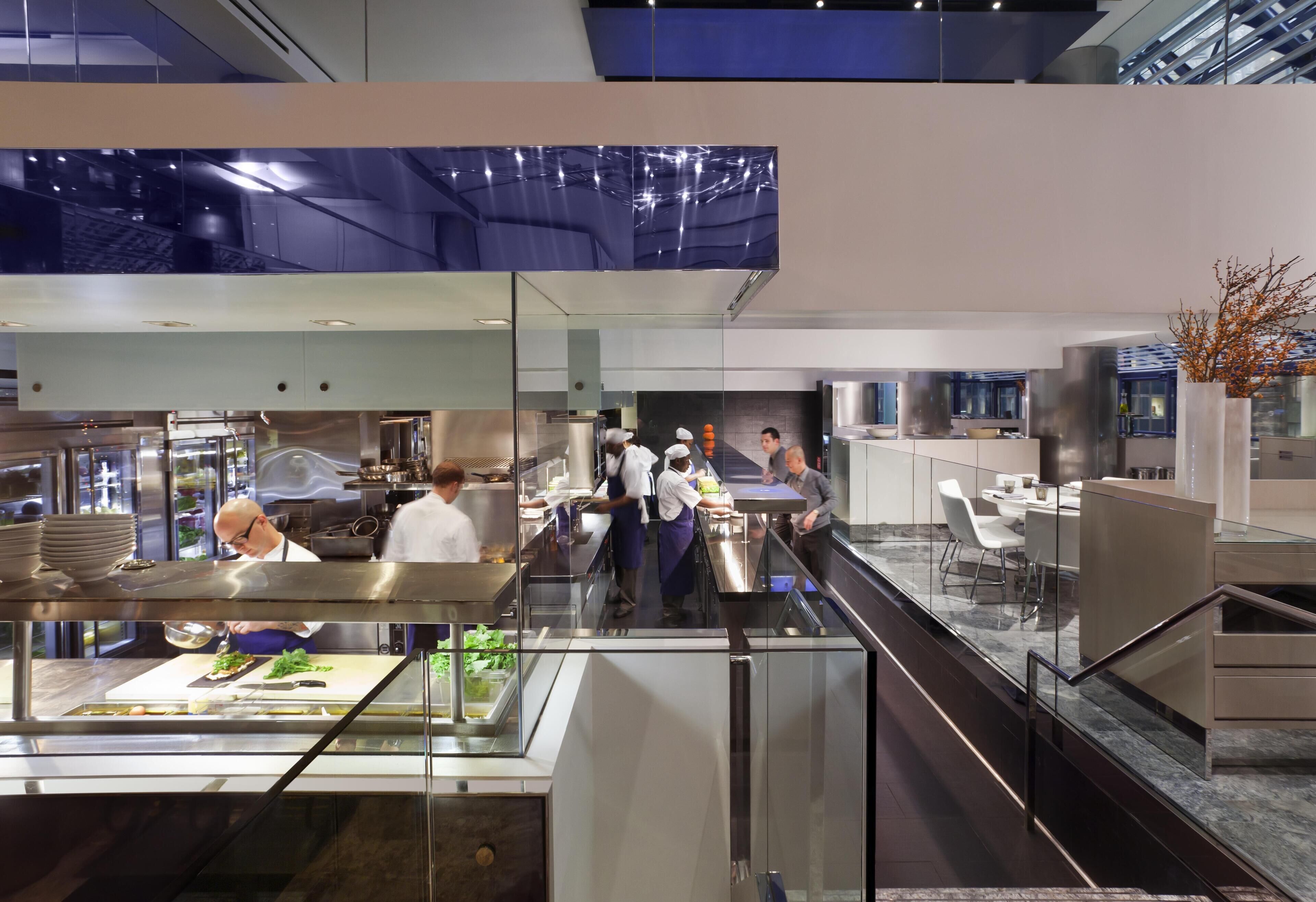 Een modern restaurant met een glazen eetgedeelte, roestvrijstalen apparatuur en uitzicht op de stad.