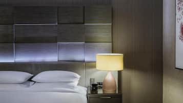 A hotel room with a modern bed, a bedside table with a lamp, and a wall-mounted artwork.