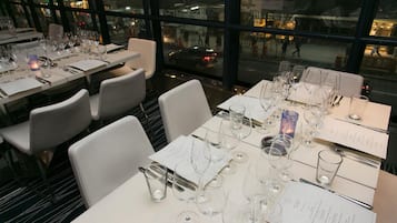A restaurant with tables set for dining, chairs, and a view of the street through large windows.