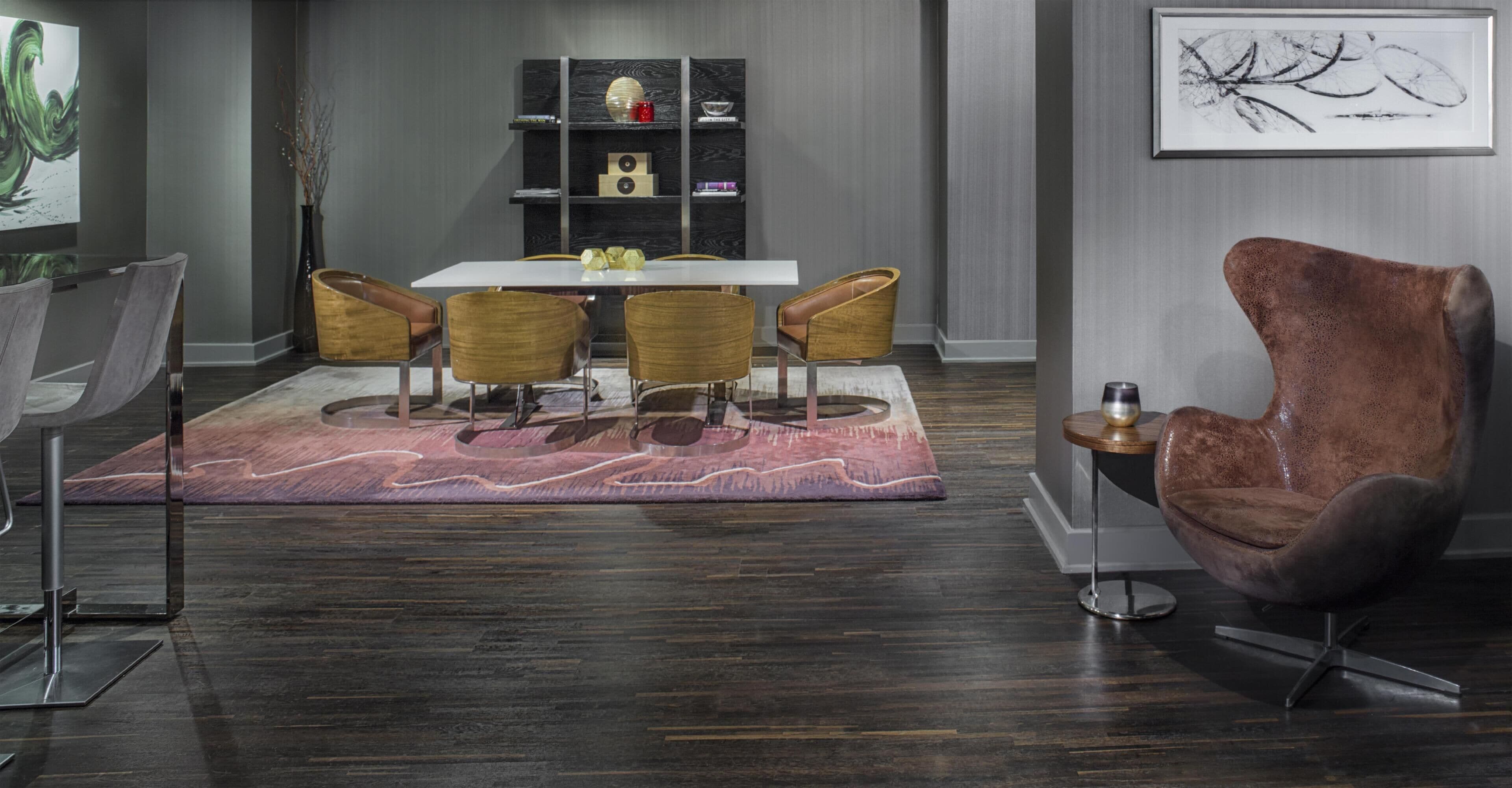 A modern dining area with a white table, four chairs, a patterned rug, and a brown armchair.