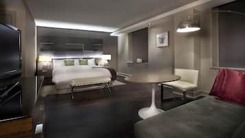 A modern hotel room with a bed, bedside tables, a TV, a round table, and a chair.