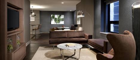 Uma sala de estar moderna com sofá, poltrona, mesa de centro e televisão de tela plana na parede.
