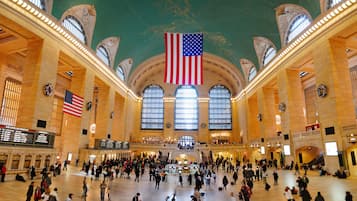 A spacious train station with high ceilings, large windows, and an American flag.