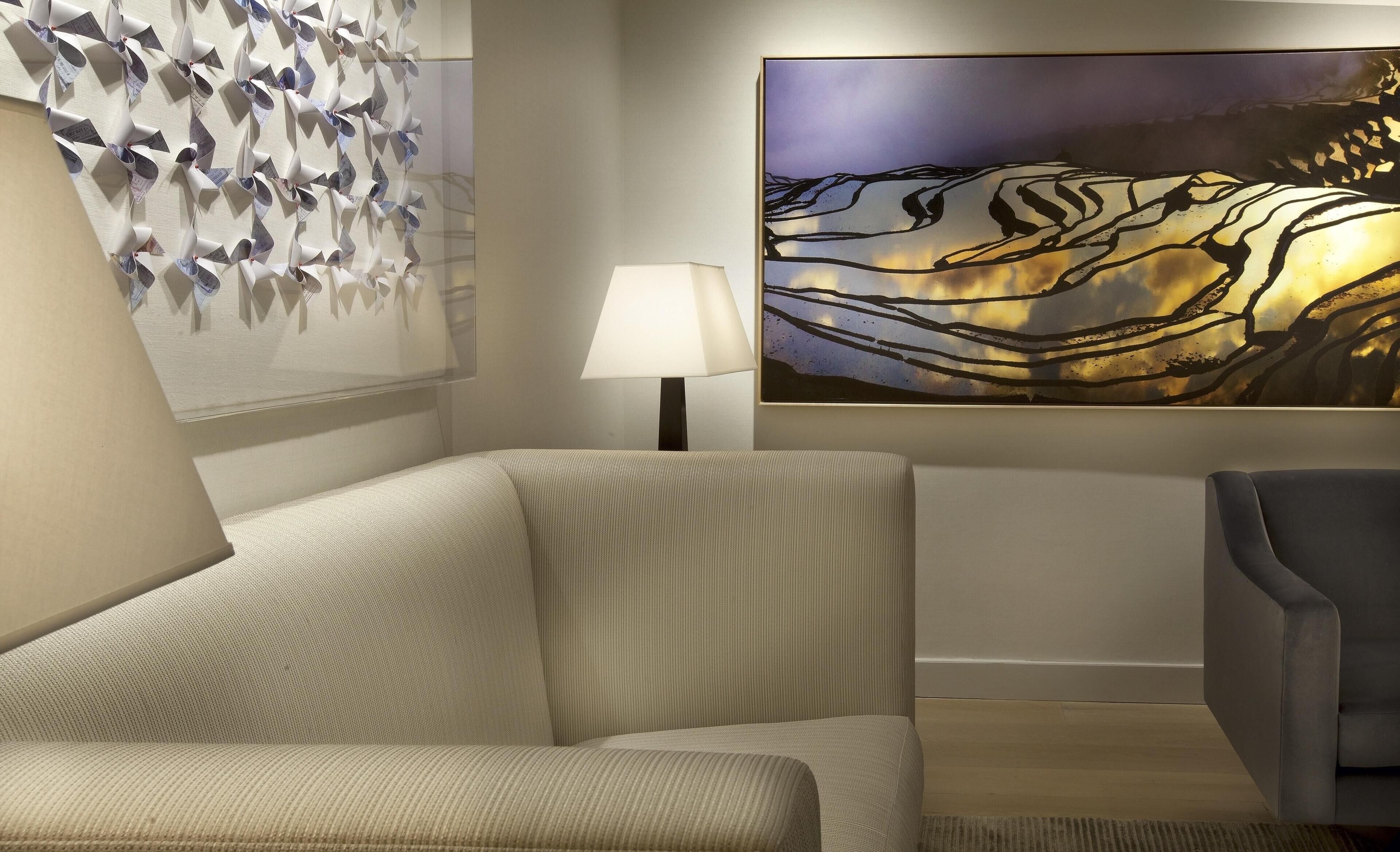 A room with a sofa, a lamp, and two paintings on the wall.