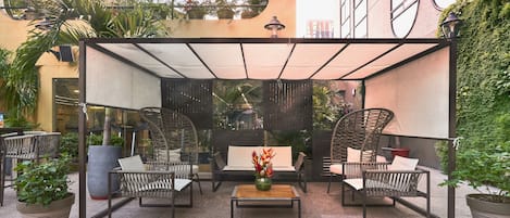 Un patio al aire libre con mobiliario de mimbre, una mesa de centro y plantas en macetas.