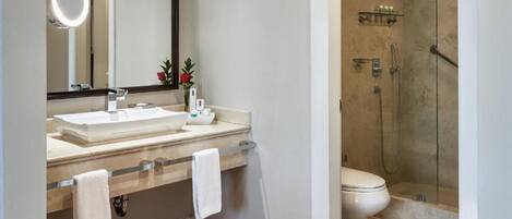 A bathroom with a large mirror, two sinks, a toilet, and a shower area.